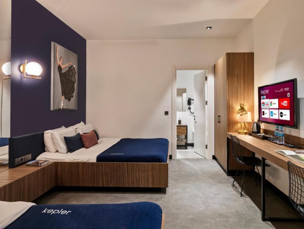 A Kepler Hotel room inside Sabiha Gökçen Airport with beds desk and wall mounted TV designed for travelers needing sleep during an Istanbul layover.