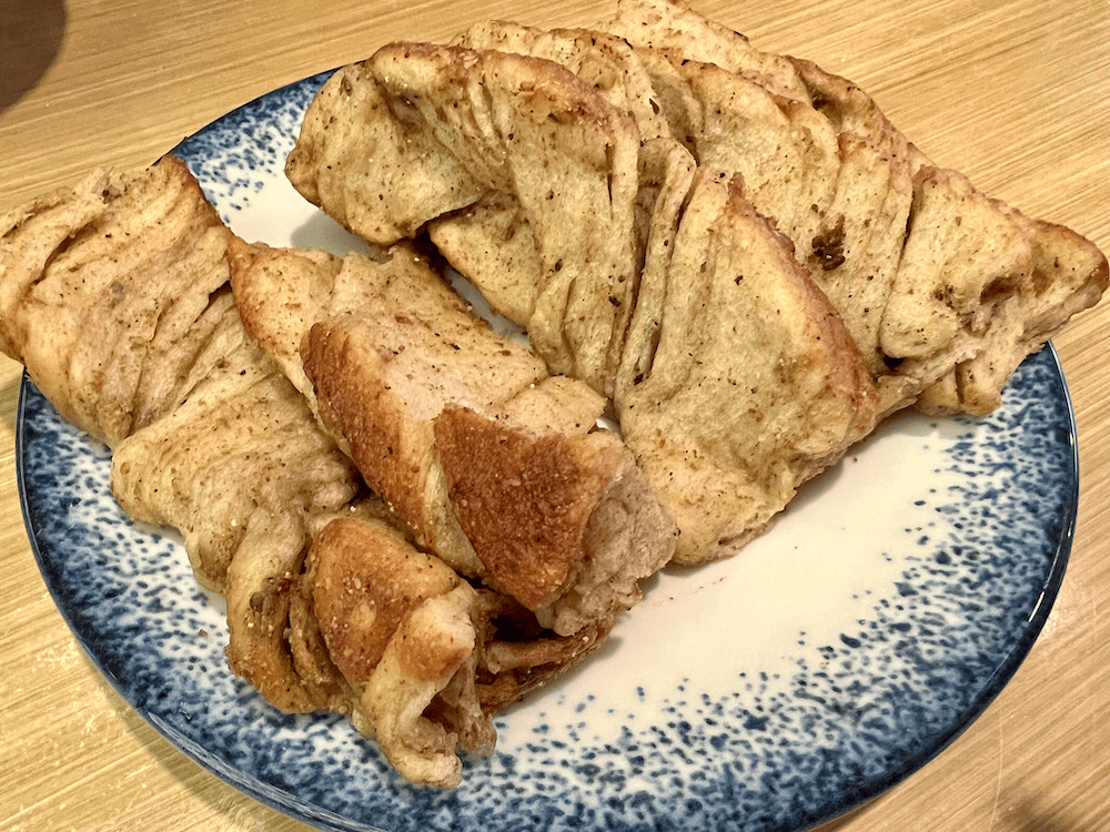 Close-up of sliced Amasya çöreği, a local spiced sweet bread, served on a blue-and-white ceramic plate atop a wooden table.