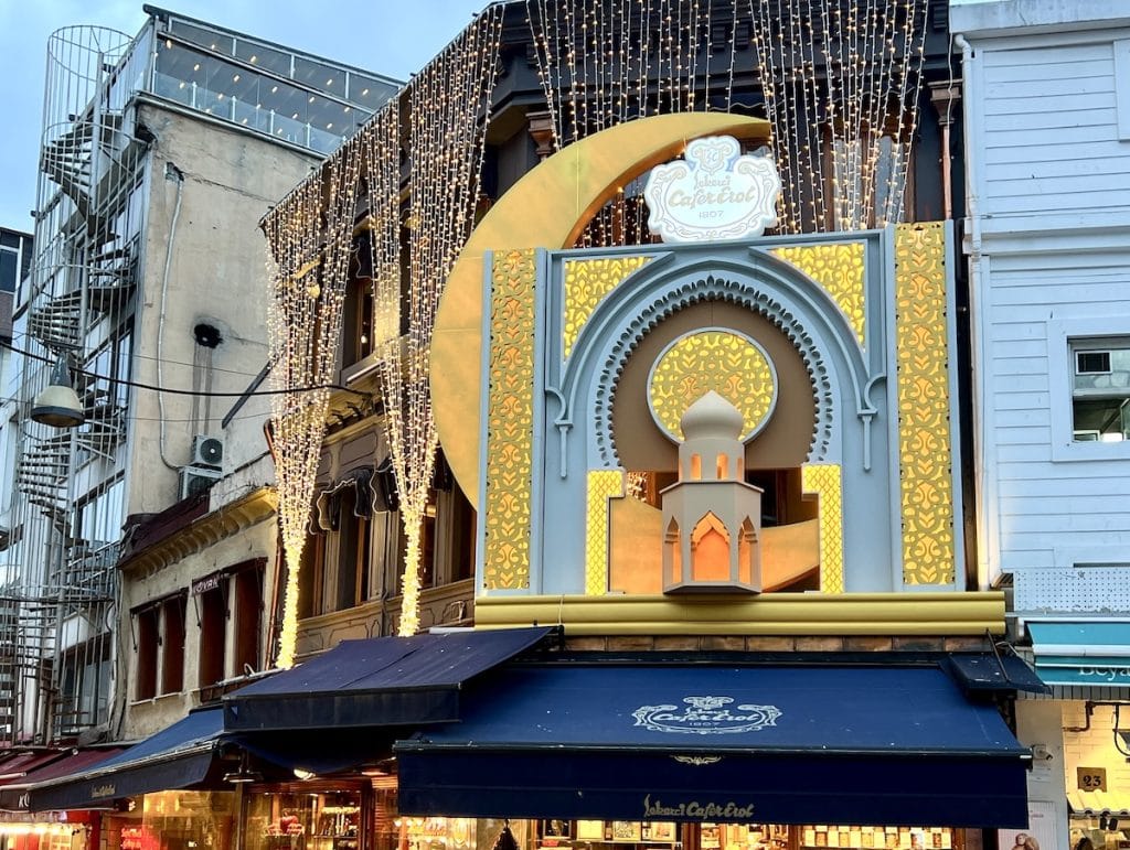 Ramadan-themed light display of Cafe Erol in Istanbul, featuring golden decorations, lights, and a large crescent moon design over the entrance.