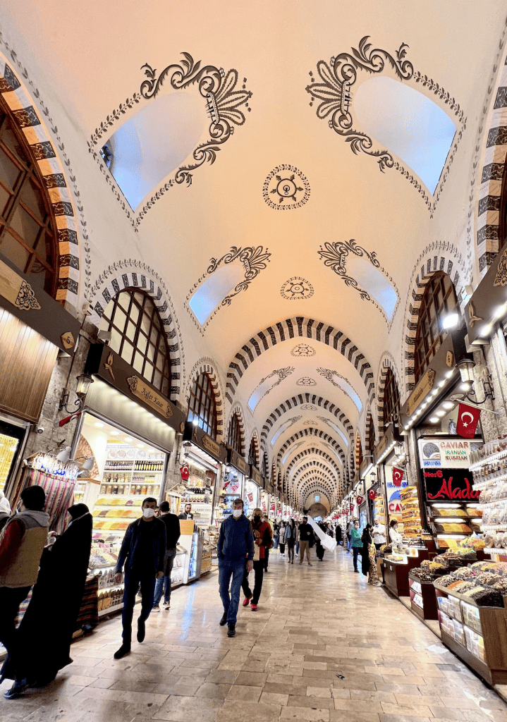 Busy corridor inside the Grand Bazaar in Istanbul with arched ceilings and rows of shops selling sweets souvenirs and spices popular for quick shopping.