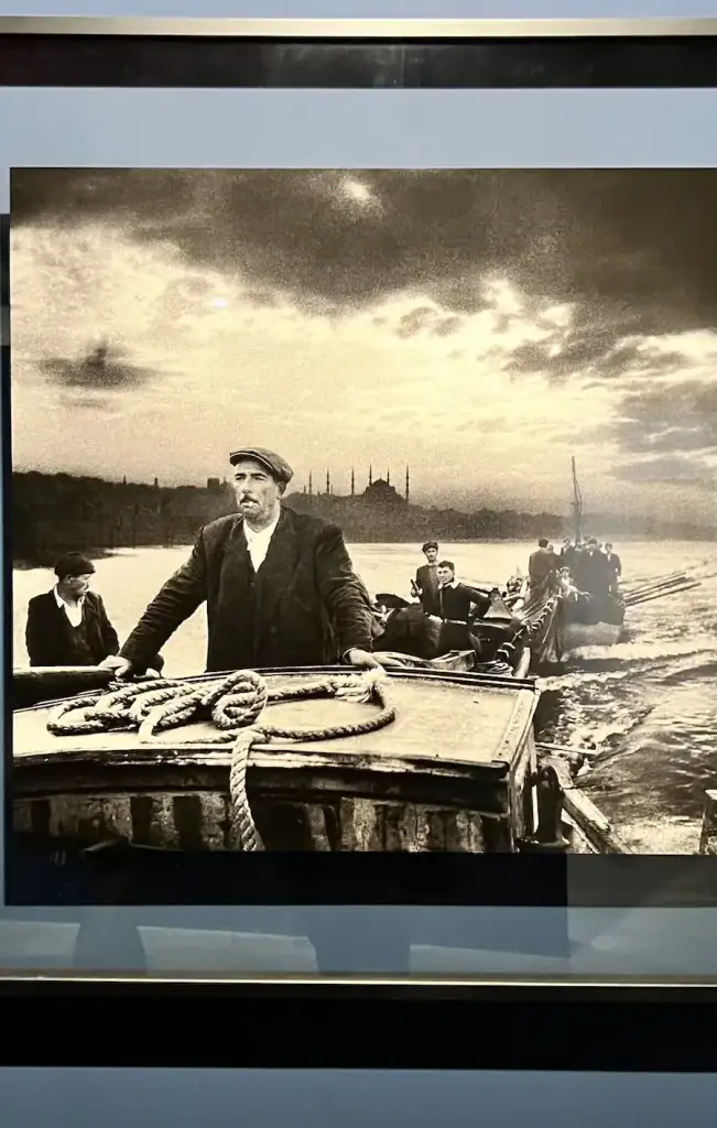 Black and white photograph of fishermen on the Bosphorus with Istanbul’s skyline in the distance at the Ara Guler Museum.