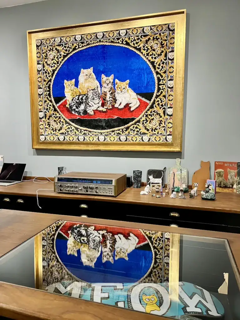 Framed tapestry of cats hanging above a retro-style desk inside a quirky shop in the Istanbul Cat Museum