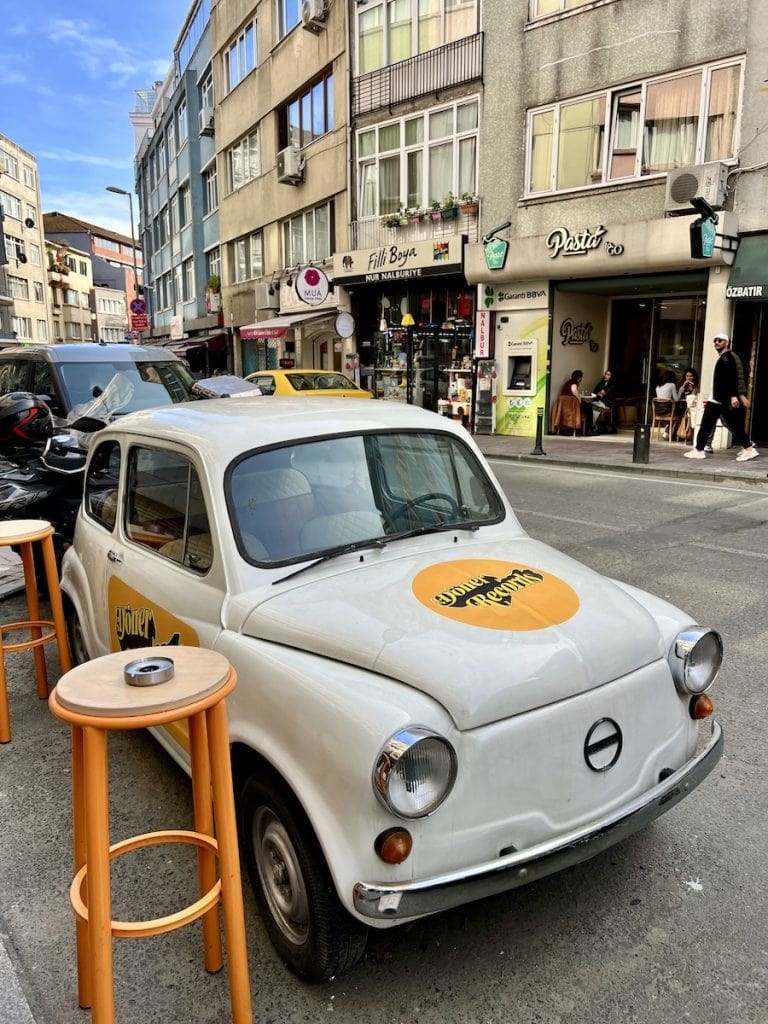 Vintage white car parked beside street tables on a lively side street in Besiktas, one of the coolest non touristy neighborhoods in Istanbul.
