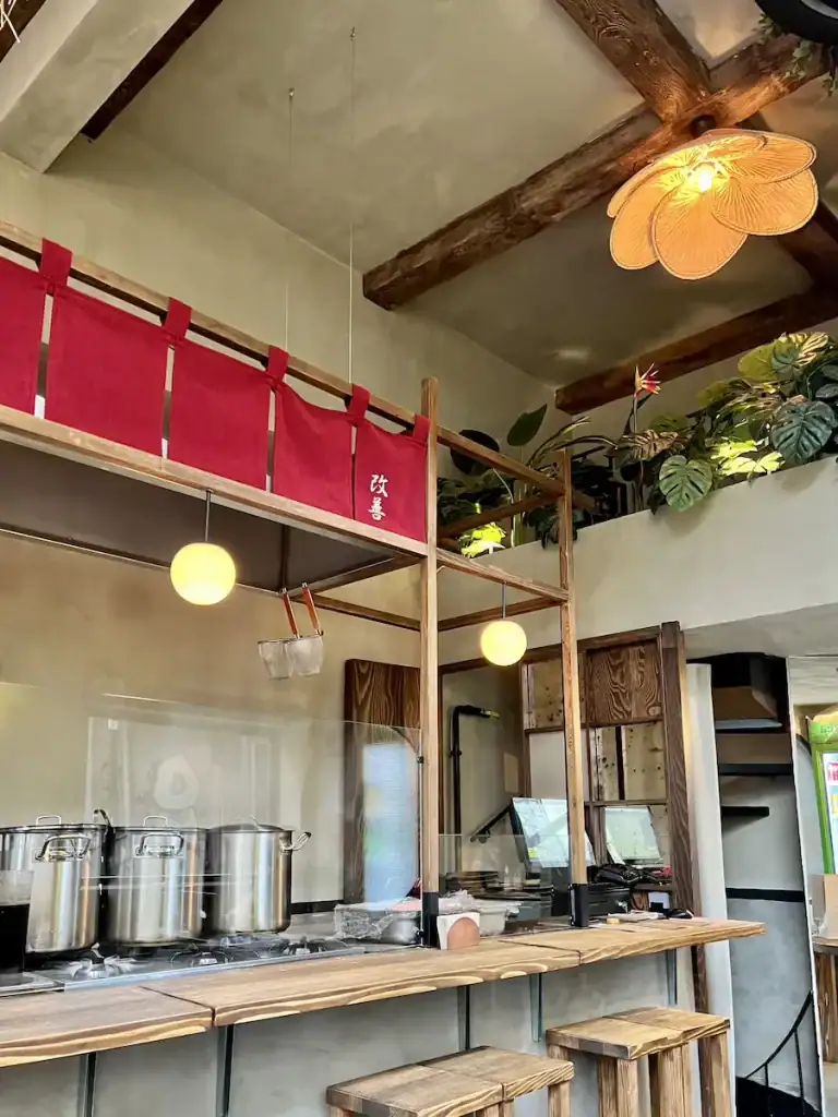 Cozy ramen bar in Besiktas with wooden counters, hanging lanterns, and an open kitchen setup.