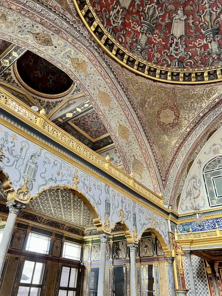 Highly decorated interior hall inside Topkapi Palace with gold details painted ceilings and marble columns showcasing historic places to visit during a layover in Istanbul.